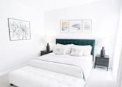 Thumbnail 3 of 9 - A white bed with a green headboard is in a room with a white wall and a black and white picture.