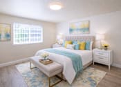 Thumbnail 3 of 9 - A bedroom with a white bed and a blue and yellow throw blanket.