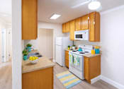 Thumbnail 4 of 9 - A kitchen with wooden cabinets and white appliances.