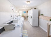 Thumbnail 8 of 9 - A white refrigerator is in the middle of a room with a white counter.
