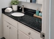 Thumbnail 5 of 12 - A bathroom with a black countertop and a white sink.