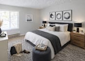 Thumbnail 4 of 12 - A bedroom with a large bed, a nightstand, and a window with blinds.