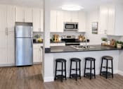 Thumbnail 6 of 12 - A kitchen with white cabinets and a stainless steel refrigerator.