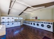 Thumbnail 10 of 11 - A laundry room with a row of washing machines.