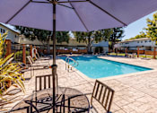Thumbnail 7 of 11 - A purple umbrella is over a table in a backyard with a pool.