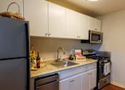 Thumbnail 4 of 6 - A kitchen with a refrigerator, microwave, and oven.