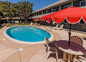 Thumbnail 5 of 6 - A pool with a table and chairs and umbrellas.