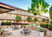 Thumbnail 8 of 13 - A courtyard with tables and chairs is surrounded by a building.