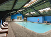 Thumbnail 9 of 13 - A large indoor swimming pool with sunroofs and lounge chairs.