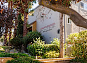 Thumbnail 7 of 7 - A tree branch is in the foreground of a building with a sign that says Camador Heights Apartment Homes.