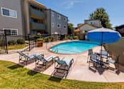 Thumbnail 4 of 7 - A pool surrounded by chairs and an umbrella in a backyard.