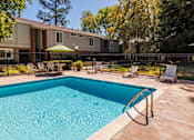 Thumbnail 8 of 9 - A swimming pool in a backyard with a fence and chairs.