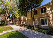 Thumbnail 7 of 9 - A row of apartment buildings with trees in front.