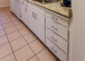 Thumbnail 4 of 5 - A kitchen with white cabinets and a granite countertop.