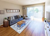 Thumbnail 3 of 7 - A living room with a grey couch, a wooden coffee table, and a blue rug.