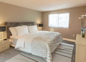 Thumbnail 2 of 7 - A bedroom with a large bed and a nightstand with a lamp.
