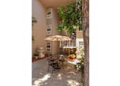Thumbnail 6 of 8 - A patio with a table and chairs under an umbrella.