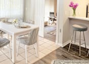 Thumbnail 2 of 8 - A dining room with a table set for two and a bar area with a stool.