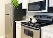 Thumbnail 3 of 8 - A black refrigerator stands next to a black microwave in a kitchen.