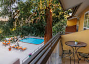 Thumbnail 5 of 8 - A patio with a table and chairs overlooking a pool.