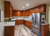 Thumbnail 5 of 12 - A modern kitchen with wooden cabinets and a stainless steel refrigerator.