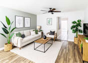 Thumbnail 1 of 11 - A living room with a white couch, a wooden coffee table, and a ceiling fan.
