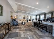 Thumbnail 6 of 10 - A modern kitchen with a large island and a dining area with a grey carpet.