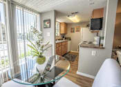 Thumbnail 3 of 10 - A kitchen with a glass table and a white fridge.