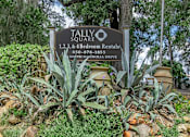 Thumbnail 1 of 7 - A sign for Tallyo Square Bed and Breakfast is surrounded by plants.