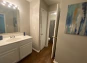Thumbnail 5 of 8 - A bathroom with a white sink and a painting on the wall.