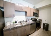 Thumbnail 14 of 47 - an apartment kitchen with stainless steel appliances and wooden cabinets