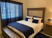 Thumbnail 25 of 47 - a bedroom with a bed and a window with blue curtains