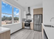 Thumbnail 25 of 63 - an empty kitchen with a large window and a stainless steel refrigerator at The Franklin Marlboro Apartments, Marlboro, NJ