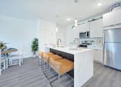 Thumbnail 7 of 11 - a kitchen with stainless steel appliances and a bar with orange stools at The Franklin at Hillsborough Apartments, New Jersey, 08844