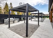 Thumbnail 33 of 63 - A modern outdoor seating area with a black metal roof and wooden flooring.