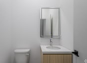 Thumbnail 60 of 63 - A bathroom with a toilet, sink and mirror.