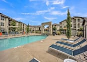 Thumbnail 14 of 22 - a resort style pool with lounge chairs and buildings in the background