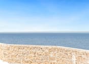 Thumbnail 12 of 12 - a view of the ocean from a balcony with a stone wall