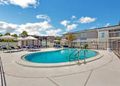 Thumbnail 9 of 12 - a swimming pool with chairs and umbrellas next to a building