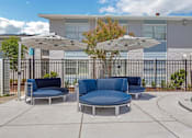 Thumbnail 11 of 12 - a patio with couches and umbrellas in front of a building