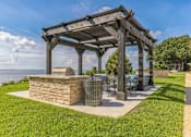 Thumbnail 12 of 19 - a picnic area with a grill and a pergola overlooking the water