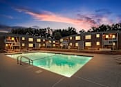 Thumbnail 11 of 19 - an apartment pool with a sunset in the background at dusk