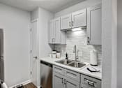 Thumbnail 2 of 13 - an empty kitchen with white cabinets and a stainless steel sink