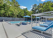 Thumbnail 15 of 18 - a pool with lounge chairs and umbrellas at The Lorient Apartments, Pensacola