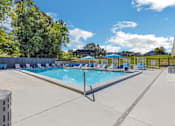Thumbnail 14 of 18 - a resort style swimming pool with blue chairs around it at The Lorient Apartments, Pensacola, FL