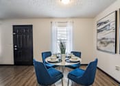 Thumbnail 7 of 18 - a dining room with a glass table and blue chairs at The Lorient Apartments, Pensacola, FL