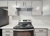 Thumbnail 3 of 16 - a kitchen with white cabinets and a stove top oven
