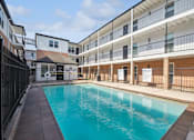 Thumbnail 12 of 16 - the pool is next to a building with a fence around it