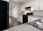 Thumbnail 2 of 6 - A modern kitchen with a black refrigerator and white cabinets.