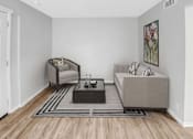 Thumbnail 4 of 9 - A living room with a grey sofa, a grey armchair, a black coffee table and a grey rug.